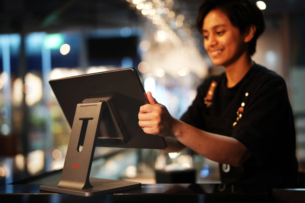 A restaurant employee using an open-source POS software terminal at a checkout counter, demonstrating modern point-of-sale use cases.